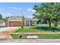 Well-maintained home with a manicured lawn, mature tree, and an attached garage with updated front door at 1930 Aster Dr, Winter Park, FL 32792