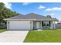 Single-Gathering home with a two-car garage, manicured lawn, and a covered entryway and small table at 2305 Ascot Ave, Orlando, FL 32833