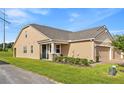 A well-maintained tan house with a green lawn, side entry and a 2 car garage at 3279 Canna Lily Pl, Clermont, FL 34711