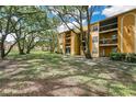 Lovely yellow apartment building featuring a well-kept lawn with mature trees providing shade and curb appeal at 5263 Images Cir # 306, Kissimmee, FL 34746