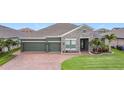 Charming single-story home featuring a three-car garage, brick paved driveway, and well-manicured lawn at 1556 Alligator St, St Cloud, FL 34771