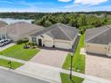 A high angle view of a suburban home featuring a well-kept lawn and a backdrop of lush greenery and a lake at 3504 Cayugas Loop, St Cloud, FL 34772