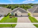 Aerial view of a charming single-story home with a brick driveway and well-maintained landscaping in a suburban setting at 3504 Cayugas Loop, St Cloud, FL 34772