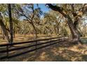 Spacious lot with mature trees and a black three-rail fence, providing a picturesque view at 63 Lake Wood Cir, Ocala, FL 34482