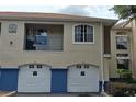 Exterior view of condo building showing tan stucco with blue accents, garage doors, and private balcony at 7220 Westpointe Blvd # 1429, Orlando, FL 32835