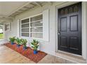 Inviting front door enhanced by potted plants, trimmed mulch, and an adjacent window with crisp white shutters at 941 Grey Oak Ct, Orlando, FL 32809