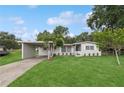 Well-maintained home featuring a covered parking area, lush lawn, and neatly arranged potted plants at 941 Grey Oak Ct, Orlando, FL 32809