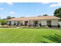 Charming single-story home featuring a lush front lawn, inviting porch with seating, and manicured landscaping at 1191 Banbury Trl, Maitland, FL 32751