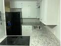Functional kitchen featuring stainless steel sink, electric cooktop, granite countertops, and white cabinets at 17836 Palm St, Umatilla, FL 32784