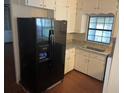Well-lit kitchen featuring sleek, modern black fridge, white cabinets, and granite countertops at 17836 Palm St, Umatilla, FL 32784
