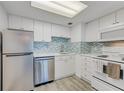 Bright kitchen featuring white cabinets, stainless steel appliances, and designer backsplash at 2700 Ocean Shore Blvd # 515, Ormond Beach, FL 32176