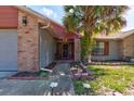 Inviting front entrance with a brick walkway, a secure screen door, and a decorative palm tree at 3237 Newmark Dr, Deltona, FL 32738