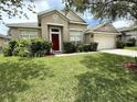 Charming single-story home with a well-manicured lawn and a vibrant red front door at 3539 Maple Ridge Loop, Kissimmee, FL 34741
