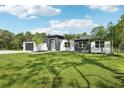 Beautiful modern home with lush green lawn, palm trees, and a striking dark and white color scheme at 42157 Tamarac St, Eustis, FL 32736