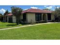 Single-story home with lawn, simple landscaping, red tile roof, and light yellow exterior at 436 Hunter Cir, Kissimmee, FL 34758
