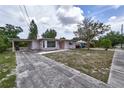 Street view of a single-story home with a long driveway and covered carport, set on a sunny day at 535 Romano Ave, Orlando, FL 32807