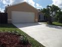 A house featuring a freshly sealed long driveway leading to a two-car garage and a mulch bed with small plants at 1021 Golfside Ct, Kissimmee, FL 34741