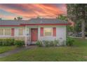 Charming single-story home with red trim, a well-manicured lawn, during a gorgeous sunset at 141 N Hill Ave # 141, Deland, FL 32724