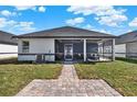 A view of the home's rear exterior showcasing a screened patio and well-maintained lawn at 3507 W Jefferson St, Orlando, FL 32805