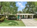 Daytime shot of a charming one-story home, highlighting its lush landscaping, turquoise door, and covered carport at 509 Altaloma Ave, Orlando, FL 32803