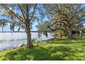Lakeside backyard view with mature trees draped in Spanish moss and lush green grass at 604 Desoto Dr, Casselberry, FL 32707