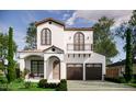 Charming two-story home showcasing a balcony, arched doorway, two-car garage, and well-manicured landscaping at 1473 Berkshire Ave, Winter Park, FL 32789