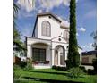 Beautiful two-story home with a covered porch, arched entrance, balcony, and lush, green landscaping at 1473 Berkshire Ave, Winter Park, FL 32789