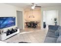 Open-concept living room featuring neutral tile flooring, comfortable seating, and a dining area with elegant lighting at 17504 Butterfly Pea Ct, Clermont, FL 34714