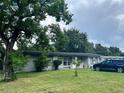 Inviting single-story home with lush landscaping, mature trees, and a car parked on the side at 223 Hope Cir, Orlando, FL 32811