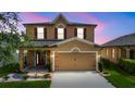 Charming two-story home with a well-manicured lawn, landscaping and a covered porch with swing at twilight at 2254 Canyon Breeze Ave, Kissimmee, FL 34746
