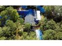 Overhead view of home with dark roof amidst lush tree cover with a covered patio at 32645 Red Oak Dr, Eustis, FL 32736