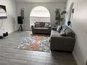 A modern living room showcasing couches, area rug and a large arched window for natural light at 5118 Laval Dr, Orlando, FL 32839