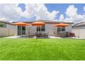 The backyard has a well-maintained lawn with outdoor seating under three umbrellas, perfect for relaxation at 840 Teton St, Haines City, FL 33844