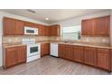 Well-lit kitchen with wooden cabinets, tile backsplash, updated appliances, and laminate wood flooring at 85 Levee Ln, Ormond Beach, FL 32174