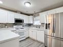 Well-lit kitchen with stainless steel refrigerator, plentiful white cabinetry, stainless microwave, and patterned backsplash at 9376 Se 175Th Pompion St, The Villages, FL 32162