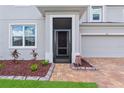 Close-up of front door showcasing tidy landscaping, brick entryway and gray exterior, enhancing curb appeal at 944 Benjamin Trl, Davenport, FL 33837