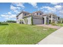 Inviting two-story home features a well-manicured lawn, brick driveway, and attached two-car garage at 13556 Abberwick Dr, Orlando, FL 32832