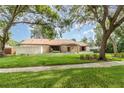 Charming single-story home with a stone facade, mature trees, and lush green lawn creating an inviting curb appeal at 1424 Mt Laurel Dr, Winter Springs, FL 32708