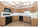 Kitchen featuring white countertops, wood cabinets and black appliances with updated flooring at 1424 Mt Laurel Dr, Winter Springs, FL 32708