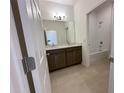 Bathroom with double vanity, tiled floors, and shower-tub combo with white tiled surround at 2043 Town Pasture Dr, Eustis, FL 32726