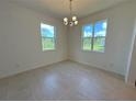 Bright dining room featuring two windows with views of the green exterior and a chandelier at 2043 Town Pasture Dr, Eustis, FL 32726