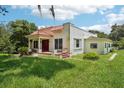Exterior view of the house with red-tiled roof and lush, overgrown lawn at 302 E Oakland Ave, Oakland, FL 34760