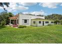 Back exterior view of the house showing an overgrown lawn and outdated windows at 302 E Oakland Ave, Oakland, FL 34760