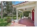Front porch with red flooring and white columns, set amidst mature landscaping at 302 E Oakland Ave, Oakland, FL 34760