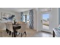 Elegantly staged dining room featuring a modern chandelier, stylish curtains, and a view of the outdoors at 33608 Seattle Slew Dr, Sorrento, FL 32776