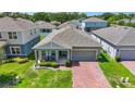Charming one-story home featuring a covered porch with seating and a brick paver driveway at 410 Winter Bliss Ln, Mount Dora, FL 32757
