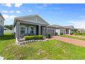 Beautifully landscaped home featuring a covered porch with seating and a brick paver driveway at 410 Winter Bliss Ln, Mount Dora, FL 32757