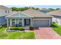 Charming one-story home with a brick driveway, covered porch with chairs, and manicured landscaping at 410 Winter Bliss Ln, Mount Dora, FL 32757