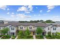 A high angle showing multiple two-story townhomes with lush landscaping against a blue sky with scattered clouds at 5030 Caspian St, St Cloud, FL 34771