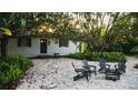 Charming outdoor stone patio with gray chairs and a fire pit under a mature tree at 610 Cypress Ave, Orange City, FL 32763
